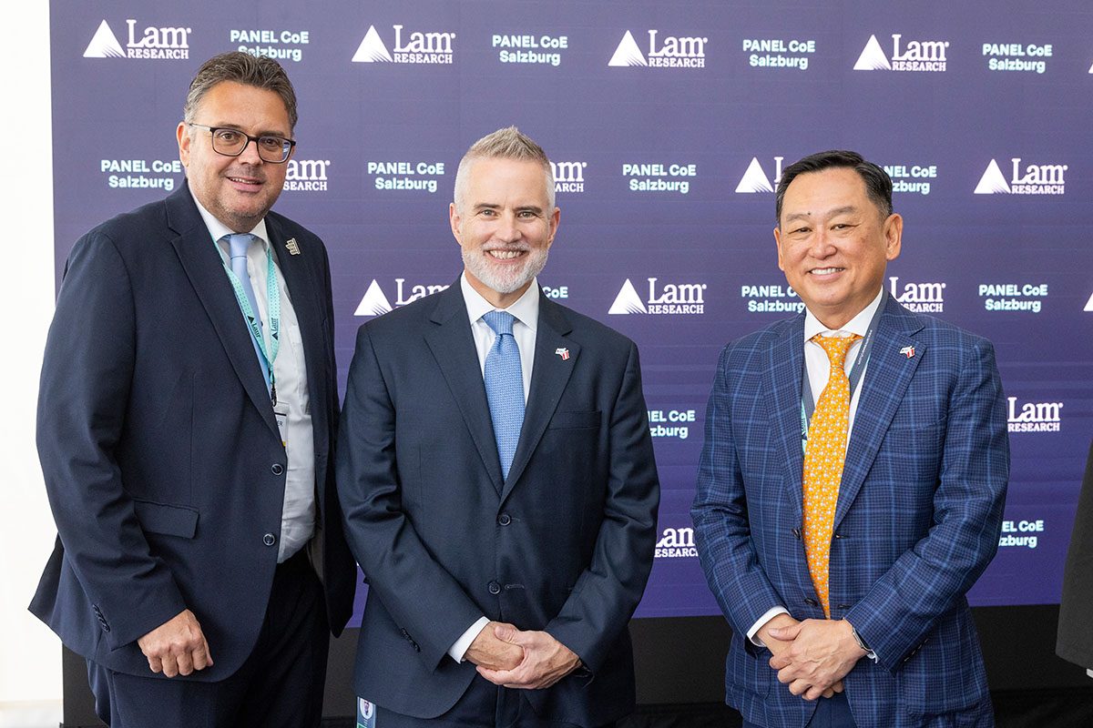 Gruppenfoto von 3 Personen bei der Eröffnung von Lam Research Salzburg vor einer Logowand