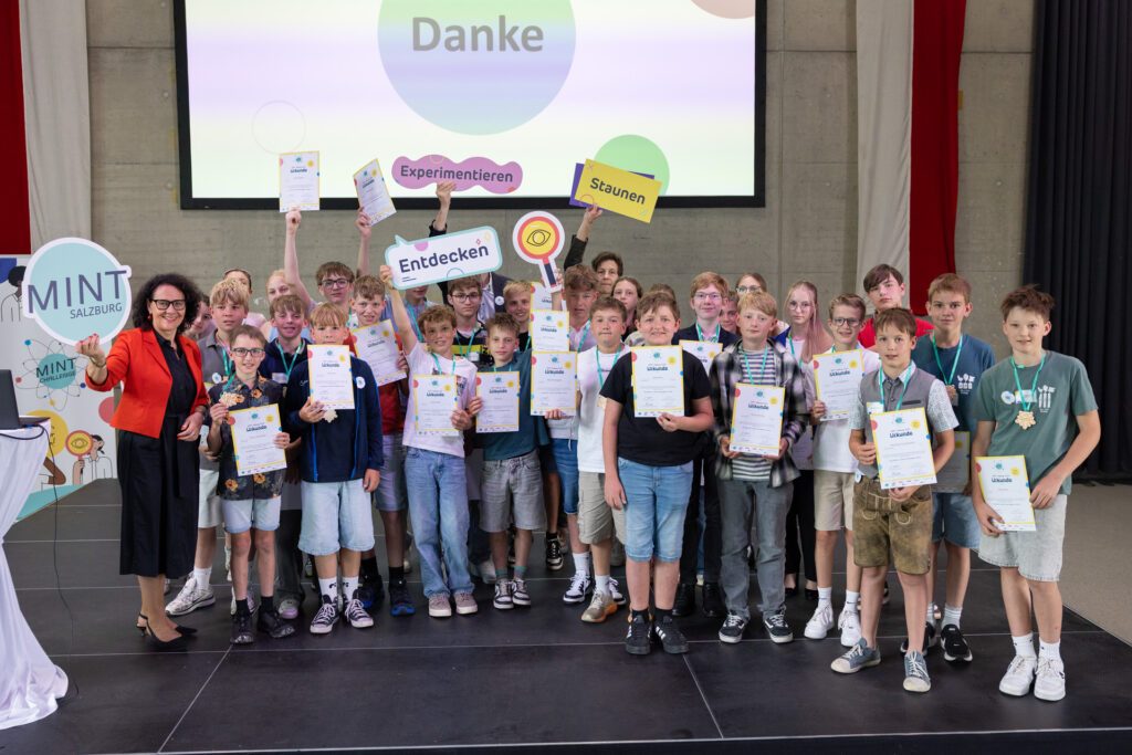 Finalistinnen und Finalisten der MINT Challenge 2026 präsentieren ihre Urkunden gemeinsam auf der Bühne beim Finale in Salzburg.