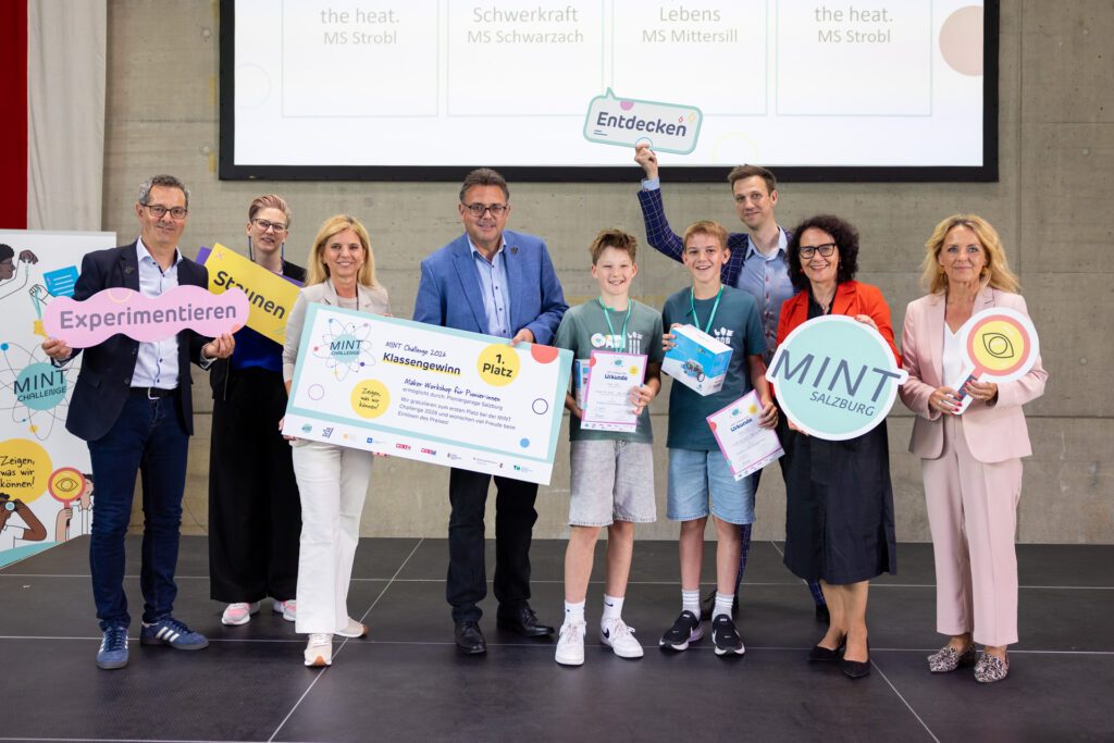 Siegerteam des ersten Platzes der MINT Challenge 2026 gemeinsam mit Vertreter:innen der Partnerorganisationen bei der Preisverleihung auf der Bühne.