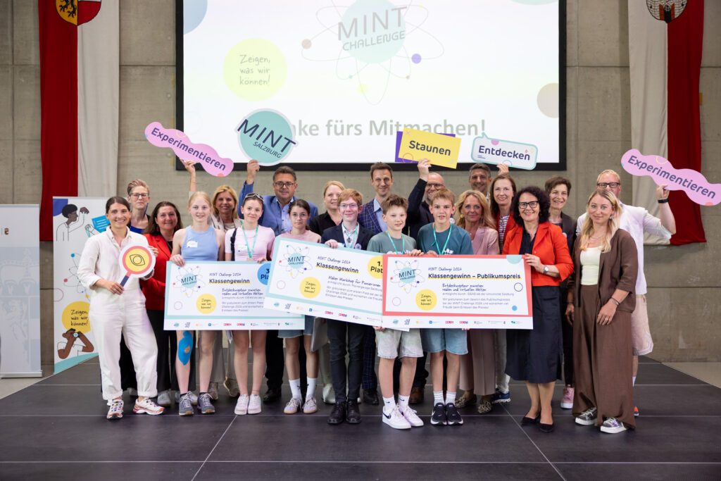 Siegerteams der MINT Challenge 2026 gemeinsam mit Vertreter:innen der Partnerorganisationen bei der Abschlussveranstaltung auf der Bühne.